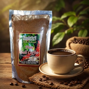 Op de afbeelding: Een doorzichtige plastic zak met gemalen koffie met een etiket met de tekst Satria Agrowisata Bali Natural Pure Bali Coffee, naast een beige keramische kop gevuld met zwarte koffie op een schoteltje, omringd door verspreide koffiebonen.