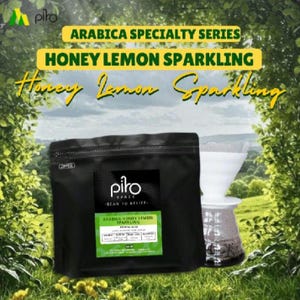 Może przedstawiać: Czarna torebka na kawę z etykietą Arabica Specialty Series Honey Lemon Sparkling oraz logo Piro Space. Obok znajduje się biały dripper do kawy na szklanej karafce. Tekst głosi Arabica Specialty Series oraz Honey Lemon Sparkling.