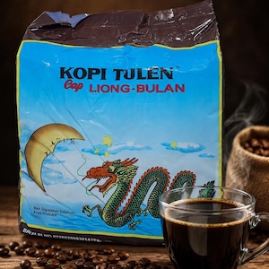 Könnte beinhalten: Eine rechteckige Kaffeetüte von Kopi Tulen Cap Liong-Bulan mit blauem Hintergrund, einer grünen Drachenillustration und einem Halbmond. Eine klare Glastasse mit schwarzem Kaffee steht neben der Tüte, umgeben von verstreuten Kaffeebohnen.