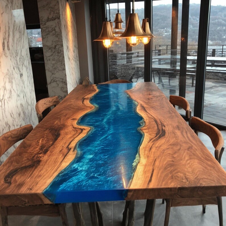 May include: A large, rectangular wooden dining table with a blue epoxy resin river running down the center. The table is surrounded by wooden chairs and illuminated by hanging pendant lights. The table is approximately 100 inches long.