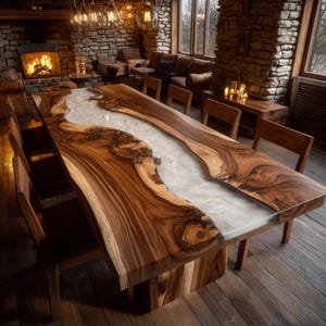 May include: A large, handcrafted wooden dining table with a river of white resin running through the center. The table is surrounded by wooden chairs and set in a rustic, well-lit dining room. The table measures approximately 120 inches long.