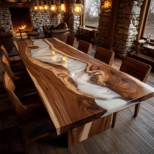 May include: A large, handcrafted wooden dining table with a river of white resin running through the center. The table is surrounded by wooden chairs. The table is approximately 10 feet long.