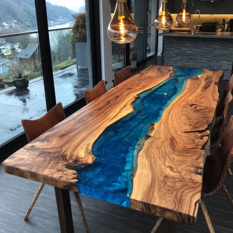 May include: A large, rectangular wooden dining table with a vibrant blue epoxy resin river running through the center. The table is made of natural wood with a warm brown tone, and is supported by dark metal legs. The table is surrounded by brown leather chairs.