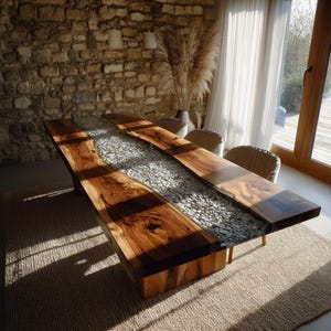 May include: A large, rectangular wooden dining table with a river of white stones running down the centre. The table is made of dark, natural wood and sits on a wooden base. The table is approximately 254 cm long.