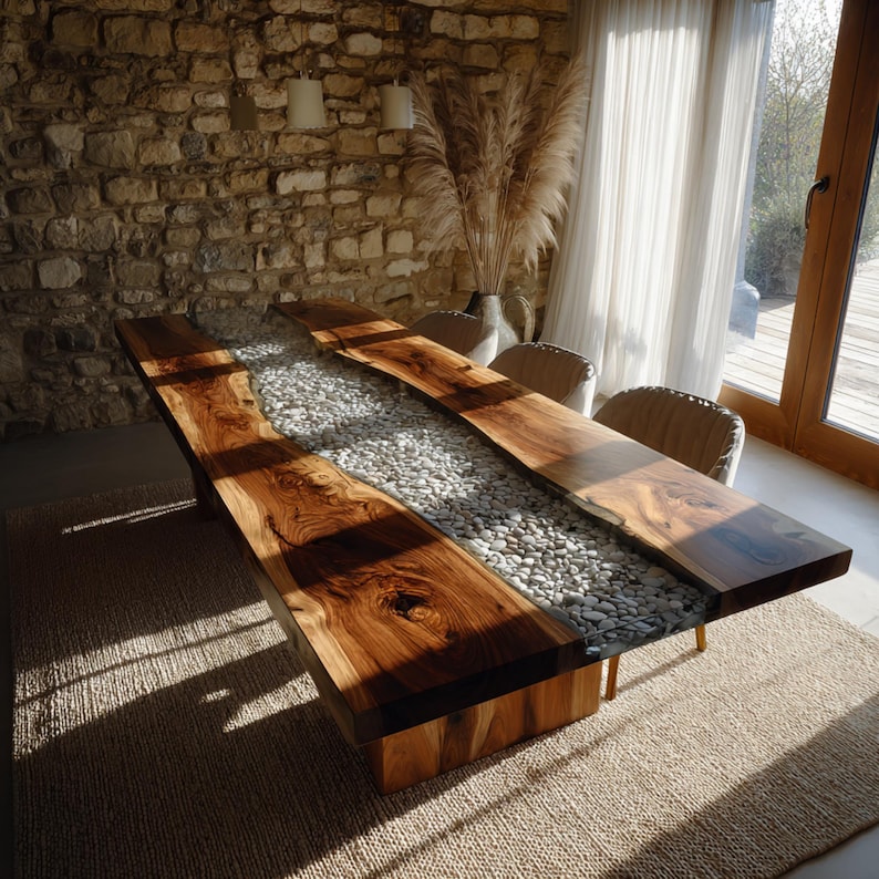 May include: A large, rectangular wooden dining table with a river of white stones running down the centre. The table is made of dark, natural wood and sits on a wooden base. The table is approximately 254 cm long.