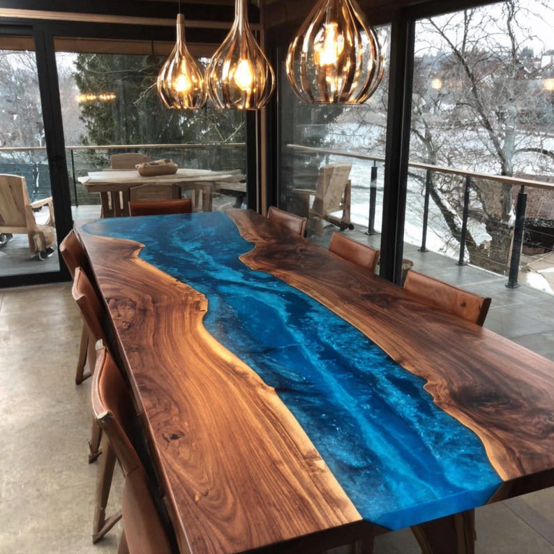 May include: A large, handcrafted dining table with a river of blue resin flowing through the center. The table is made of dark wood and has a glossy finish. Brown leather chairs surround the table, and the room has large windows.