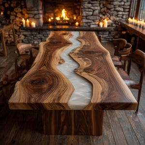 May include: A large, handcrafted wooden dining table with a unique design. The table features a live edge, showcasing the natural wood grain, and a central river of white resin. The table is supported by a solid wooden base, creating a rustic yet elegant aesthetic.