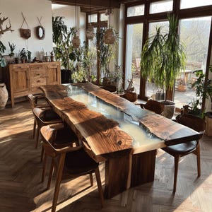 Op de afbeelding: Een grote, handgemaakte houten eettafel met een live edge design. De tafel heeft een lichtgekleurde epoxyharsrivier in het midden. Verschillende houten stoelen met leren zittingen omringen de tafel en cre&euml;ren een rustieke en elegante eethoek.