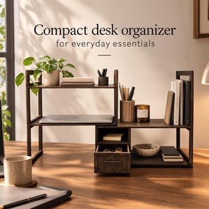 May include: A dark brown wooden desk organizer with multiple shelves, a small drawer, and open compartments. The text "Compact desk organizer for everyday essentials" is displayed above the unit, which holds books, a plant, and stationery.