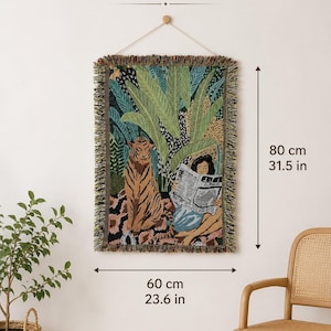 May include: A rectangular woven wall tapestry featuring a tiger and a person reading a newspaper amidst tropical foliage. The tapestry has fringed edges and measures 31.5 inches in height by 23.6 inches in width, as indicated by the text and arrows.