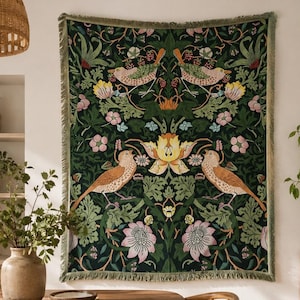 May include: A rectangular woven wall tapestry featuring a dark green background with a symmetrical pattern of birds, large yellow and pink flowers, and green foliage. The tapestry has a fringed edge and is displayed hanging on a wall.