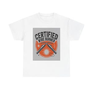 May include: A white t-shirt featuring a graphic design with the text "CERTIFIED WIRE BURNER" in black letters. The design includes two crossed welding torches over an orange circle on a grey background, with small star-like accents.