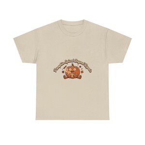 May include: A beige short-sleeve t-shirt featuring a central graphic of an orange pumpkin character with swirling eyes holding a steaming mug. The text above the pumpkin reads "Pumpkin Spiced Beyond Repair" in a brown, curved, retro-style font.
