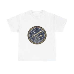 May include: A white short-sleeve t-shirt featuring a circular graphic on the chest. The design depicts a telescope, a crescent moon, and a planet against a dark blue starry background, with the text AMATEUR ASTRONOMER, PROFESSIONAL STARGAZER, BACKYARD ASTRONOMER CLUB.