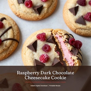 May include: Close-up of several raspberry dark chocolate cheesecake cookies. The cookies are round, with a light brown exterior, and are decorated with fresh raspberries and dark chocolate chunks. One cookie is cut open, revealing a pink filling.