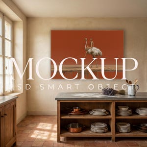 May include: A rectangular wall art print featuring a person riding an ostrich against a solid burnt orange background, displayed in a kitchen with a wooden island, stacked white ceramic plates, copper cookware, and a white pitcher.