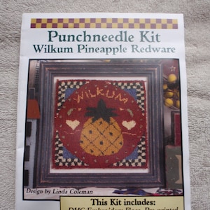May include: Punchneedle kit for a Wilkum Pineapple Redware design. The kit includes DMC embroidery floss, pre-printed fabric, and a full color chart. The image shows a framed piece of punchneedle embroidery with a pineapple design and the word "Wilkum" above it.
