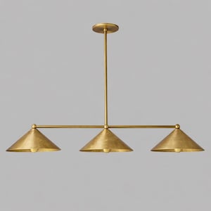 A linear chandelier featuring a central vertical rod connected to a horizontal bar that supports three downward-facing conical shades. The entire fixture is finished in a brushed brass tone with a smooth, metallic surface texture.