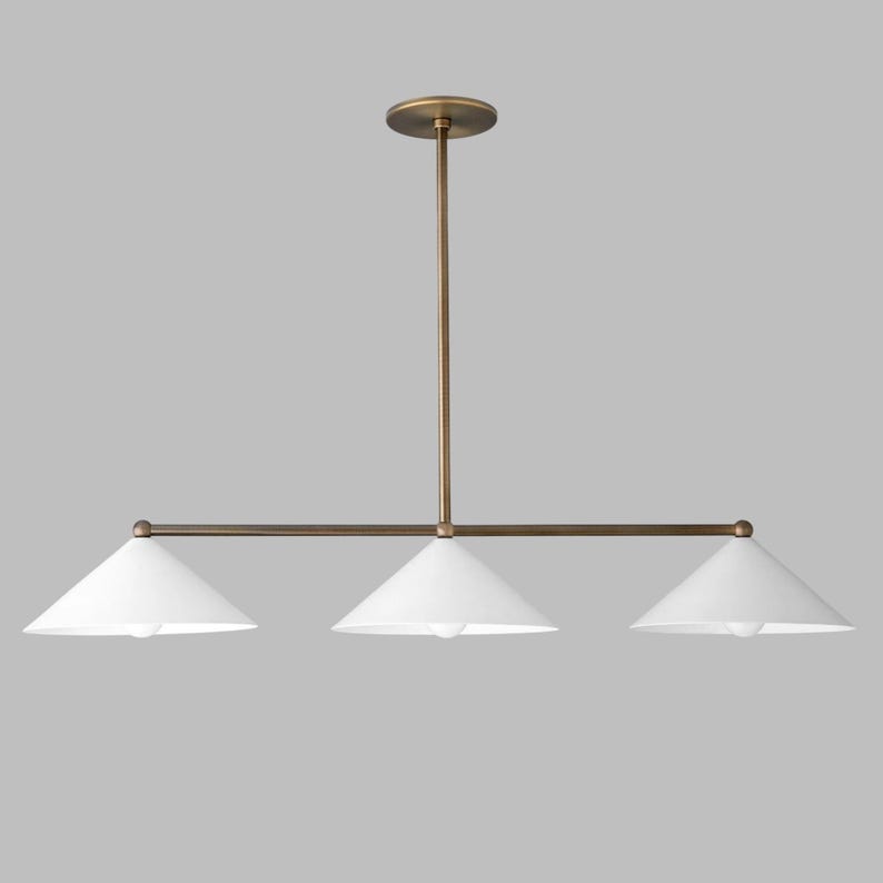 May include: A linear pendant light fixture featuring a central vertical rod connected to a horizontal bar that supports three white conical shades. The metal components have a muted bronze finish, and the design includes a circular ceiling canopy.