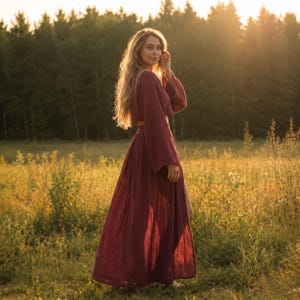 May include: A two-piece set consisting of a long-sleeved, cropped top and a matching floor-length, pleated maxi skirt. The garment is made of a textured, deep burgundy fabric with a loose, flowing silhouette and wide sleeves.