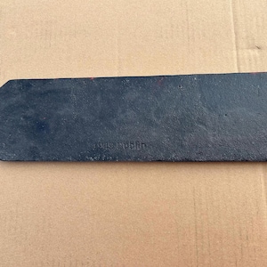 Op de afbeelding: Een rechthoekig zwart metalen bord met een puntig uiteinde, voorzien van de in reli&euml;f aangebrachte tekst 1949 Dublin. Het stuk heeft een getextureerd oppervlak en bevat drie kleine ronde gaten voor montage, met vage rode verfmarkeringen.
