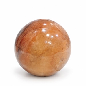 May include: A polished, spherical stone object featuring a warm, variegated colour palette of amber, tan, and deep brown tones. The surface exhibits natural swirling patterns and inclusions, with a smooth, reflective finish that catches the light.