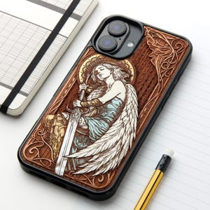 Peut inclure: Une coque de smartphone noire avec une incrustation en bois sculpté représentant un ange aux grandes ailes tenant une longue épée. Le motif comprend des détails en filigrane, une auréole dorée et des touches de bleu sur les vêtements de l'ange.