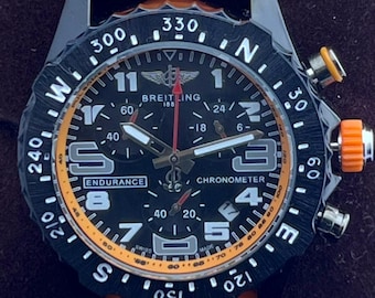 Orologio da polso vintage Breitling 1884 Endurance Chronometer al quarzo con quadrante nero, cinturino in caucciù arancione, cassa nera, lunetta girevole e datario/secondi.