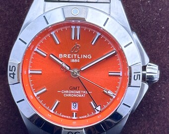 Orologio da polso vintage Breitling 1884 GMT Twin-Time Automatic con quadrante arancione, cassa e bracciale in acciaio inossidabile, datario funzionante e lunetta girevole da uomo.