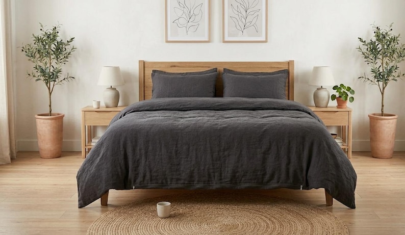 Charcoal gray linen bedding set on a wooden bed in a bright minimalist bedroom, featuring soft washed linen texture, neutral decor, natural light, and modern Scandinavian styling.
