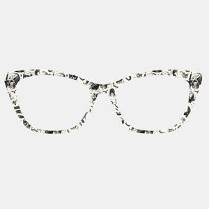 May include: Cat-eye style eyeglasses with a black and white skull pattern. The frames have a cream-colored background with a repeating pattern of skulls and other small images. The lenses are clear.