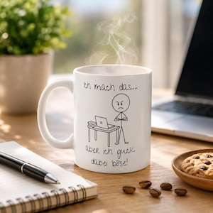 Könnte beinhalten: Ein weißer Keramikbecher mit einer schwarzen Strichzeichnung einer Strichmännchen-Figur, die an einem Schreibtisch mit Laptop steht, und dem deutschen Text "Ich mach das.... aber ich guck dabei böse!". Dampf steigt aus dem Becher auf.