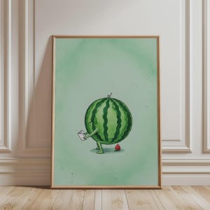 May include: A framed wall art print featuring a green watermelon character with arms and legs, holding a small white book. A tiny snail sits on top of the watermelon, and a small red object rests on the floor near its feet, set against a light green background.