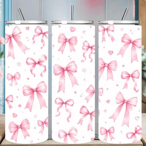 Puede incluir: Un vaso cilíndrico blanco con un patrón repetitivo de lazos de acuarela rosa claro y corazones pequeños. El vaso incluye una tapa transparente y una pajita de metal delgada que sobresale por la parte superior, mostrando un diseño uniforme en toda la superficie.