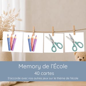 May include: Four square white cards hanging from a string with wooden clips. Two cards feature watercolor illustrations of three colored pencils, and two cards feature watercolor illustrations of teal scissors. Text reads Memory de l'École 40 cartes.