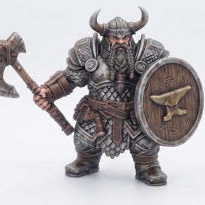 Peut inclure: Une figurine miniature peinte représentant un guerrier nain barbu portant une armure en écailles grises et un casque à cornes. Le personnage tient une grande hache de combat dans la main droite et un bouclier rond en bois avec une enclume dorée.