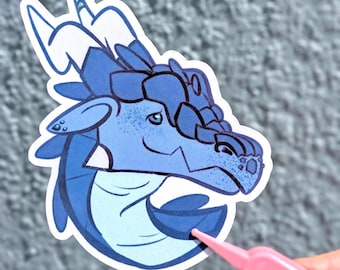 May include: A die-cut vinyl sticker featuring a stylised blue dragon head with dark blue scales, a light blue neck, and prominent horns. The dragon has a gentle expression with visible line art details and a white border outline.