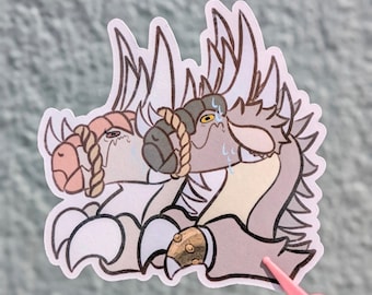 May include: A die-cut sticker featuring two stylised, reptilian creatures with spiked crests, tan and grey skin tones, and rope-like collars around their necks. The creatures have expressive eyes, visible sweat droplets, and clawed hands, rendered in a clean, outlined illustration style.