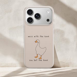 以下が含まれることがあります： ベージュのスマートフォンケース。オレンジ色の足とくちばしを持ち、ナイフをくわえた白いガチョウの線画イラストが描かれています。ガチョウの上に「mess with the honk」、下に「you get the bonk」という文字が記されています。