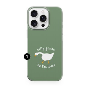 以下が含まれることがあります： セージグリーンのスマートフォンケース。オレンジ色のくちばしと足を持つガチョウの白いグラフィックが描かれています。ガチョウのイラストの上下に「silly goose on the loose」という白い文字がプリントされています。数字の1が入った黒い円。