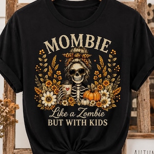 May include: A vintage black t-shirt featuring a graphic of a skeleton with a messy bun, leopard print headband, and sunglasses, holding a coffee cup. The design includes autumn flowers, wheat, and pumpkins with the text MOMBIE Like a Zombie BUT WITH KIDS.