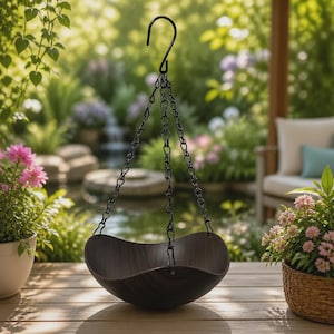 Puede incluir: Una maceta colgante en forma de cuenco de color marrón oscuro con una textura de veta de madera lisa. La maceta está suspendida por tres cadenas de metal negro que convergen en un gancho en S negro, diseñada para sostener plantas u objetos.