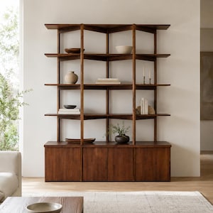 Peut inclure: Une grande étagère en bois foncé composée d'une base à quatre portes et de cinq niveaux d'étagères ouvertes. La structure comprend des supports verticaux et des planches horizontales, décorées de bols en céramique, de livres et d'une plante.