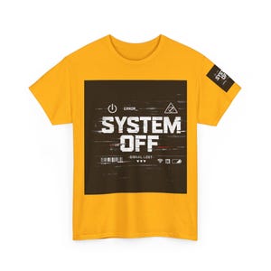 Può includere: Una t-shirt a maniche corte color giallo senape con una grande grafica quadrata nera sul petto che riporta il testo bianco SYSTEM OFF, ERROR e SIGNAL LOST, insieme a varie icone digitali tra cui un simbolo di accensione e una batteria.