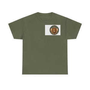 Può includere: Una t-shirt a maniche corte color verde oliva con una grafica circolare sul petto sinistro. La grafica raffigura una testa di leone con il testo THE ROYAL SAVANNA, SAVANNA KING e WHOLE LION stampato in un bordo circolare su uno sfondo al tramonto.