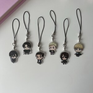 Puede incluir: Siete colgantes de personajes de estilo anime con cordones negros. Los colgantes presentan varios personajes con rasgos faciales y ropa detallados. Los colgantes son de color plateado y están dispuestos sobre una superficie blanca.