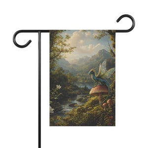Puede incluir: Una bandera de jardín con una escena de fantasía de un dragón azul sobre una seta. La imagen muestra un bosque con un río, montañas y un cielo nublado. La bandera está montada en un soporte de metal negro.