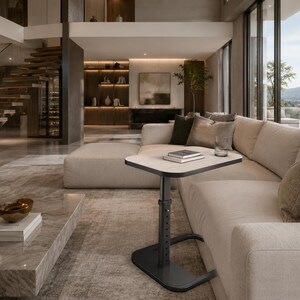 May include: A modern living room with a beige sectional sofa, a marble coffee table, and a height-adjustable side table. The side table has a square top and a black base. A glass of water and books are on the side table.
