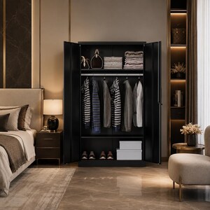 May include: A black wardrobe with open doors, revealing hanging clothes, folded towels, and storage boxes. The wardrobe is in a bedroom setting, with a bed, nightstand, and a chair visible. The room has a neutral color palette.