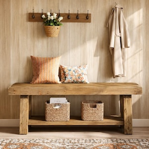 May include: A rustic wooden bench with a lower shelf holding two woven baskets, topped with an orange striped pillow and a floral patterned pillow. A wall-mounted coat rack with white flowers in a hanging basket and a beige coat are above.